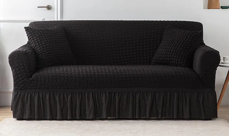 Black fabric sofa cover with ruffled skirt and cushions in Dubai home